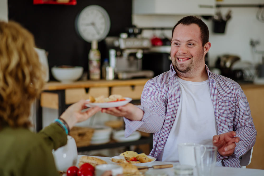 Person smiling while serving food at a table.